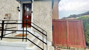 Ein Haus mit einer Holztür, einem roten Tor und einer Treppe, die zum Eingang führt.