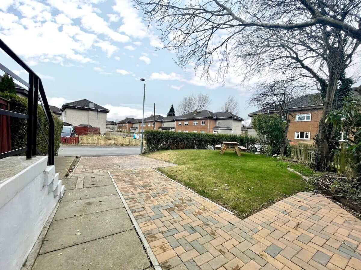 Una calle residencial con un camino pavimentado que conduce a una zona verde.