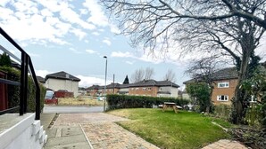 Eine Wohnstraße mit einem gepflasterten Weg, der zu einer Grünfläche führt.