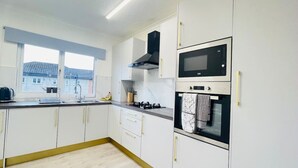 Eine moderne Küche mit weißen Schränken, einem Gasherd, einer Mikrowelle und einem eingebauten Backofen.