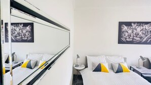 Ein Hotelzimmer mit einem Bett, einem Nachttisch, einer Lampe und zwei Wandbildern mit Tiger-Motiv.