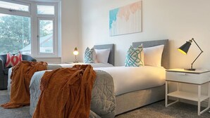 A bedroom with a bed, bedside table, lamp, and a window.