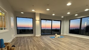 A spacious room with large windows, a wooden floor, and a dog resting on a mat. - 2 Bed in Abbotsham (oc-g28822) (Abbotsham)