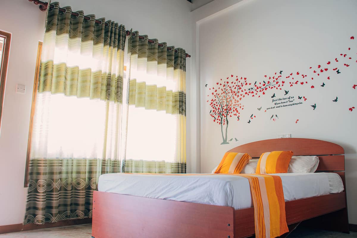 A bedroom with a bed, curtains, and a wall decal.