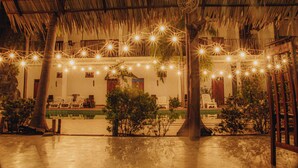 An outdoor area with a thatched roof, string lights, and a pool. - Shell Resort Arugambay (Arugam Bay)
