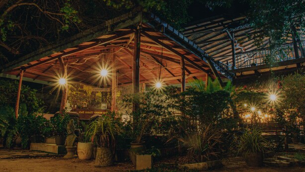 A covered outdoor area with a wooden structure, potted plants, and a staircase. - Shell Resort Arugambay (Arugam Bay)