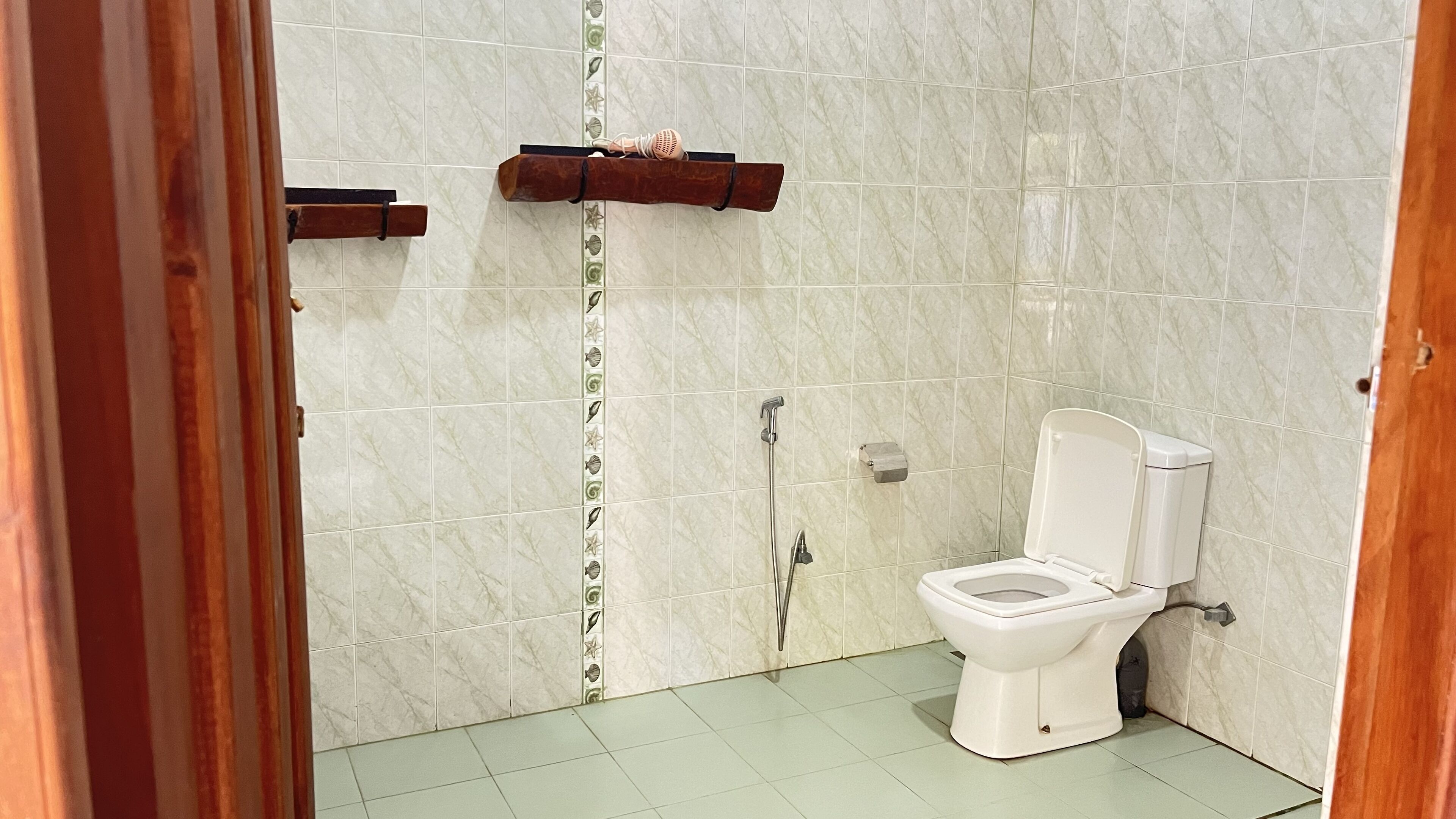 A bathroom with a toilet, a shower, and a towel rack.