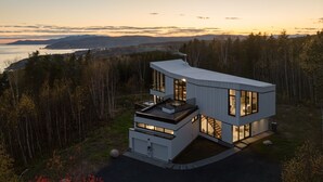 Una casa moderna a due piani con tetto piatto, ampie finestre e un balcone.