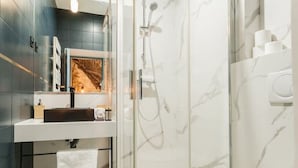 Un bany modern amb dutxa tancada per vidre, un vàter blanc i un lavabo amb mirall.