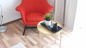 Ein modernes Wohnzimmer mit einem roten Sessel, einem kleinen runden Tisch mit Pflanze und einer Heizung.