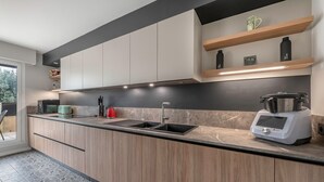 Una cocina moderna con armarios de madera, encimera negra, pileta integrada y cafetera.