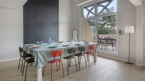 Un comedor con una mesa preparada para seis personas, sillas y un ventanal con vistas a árboles.