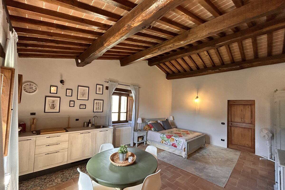 Una habitación acogedora con una cama, una mesa de comedor con sillas, una zona de cocina y un baño.