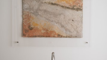 A bathroom with a wall-mounted artwork and a modern faucet.