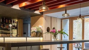 Zona de bar con varios taburetes, una barra y una variedad de botellas.