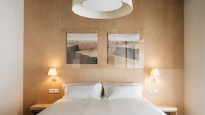 Una habitación de hotel con una cama grande, dos lámparas de noche y una obra de arte colgada en la pared.