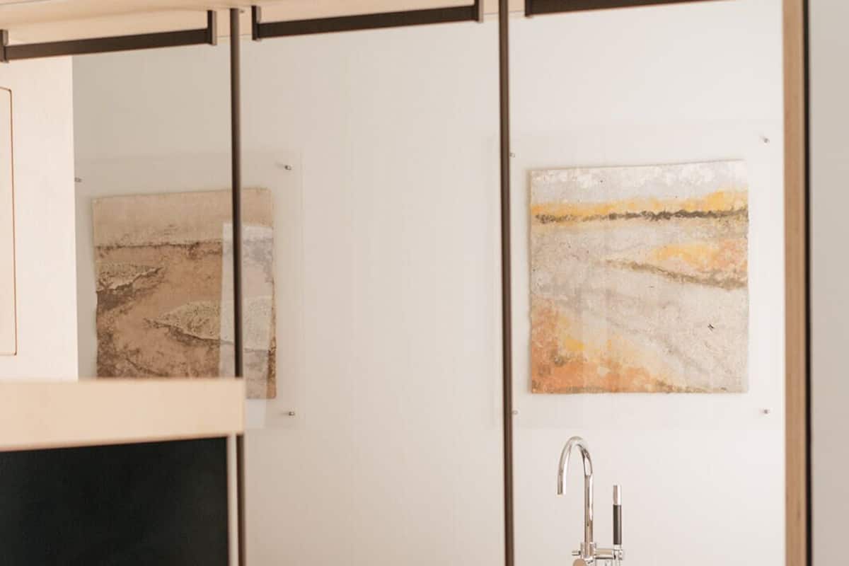 A modern hotel room with a bed, a sink, and artwork on the walls.