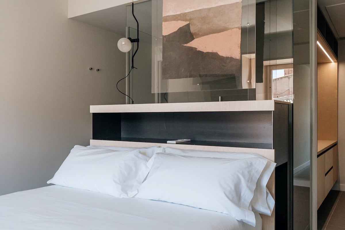 A modern bedroom with a bed, a built-in shelf, and a glass partition.