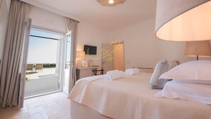 Hotellihuone, jossa on suuri sänky, työpöytä ja näkymä ulos.