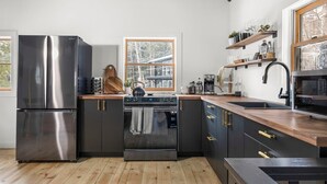 Une cuisine moderne dotée d’appareils électroménagers en acier inoxydable, de plans de travail en bois et d’une grande fenêtre qui laisse entrer la lumière naturelle.