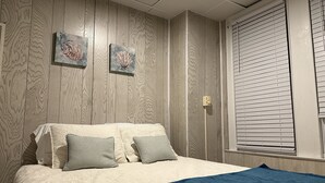 A bedroom with a bed, two pillows, a blue blanket, and two wall-mounted artworks. - Best Location in AC! Near Boardwalk, Casino Action (Atlantic City)
