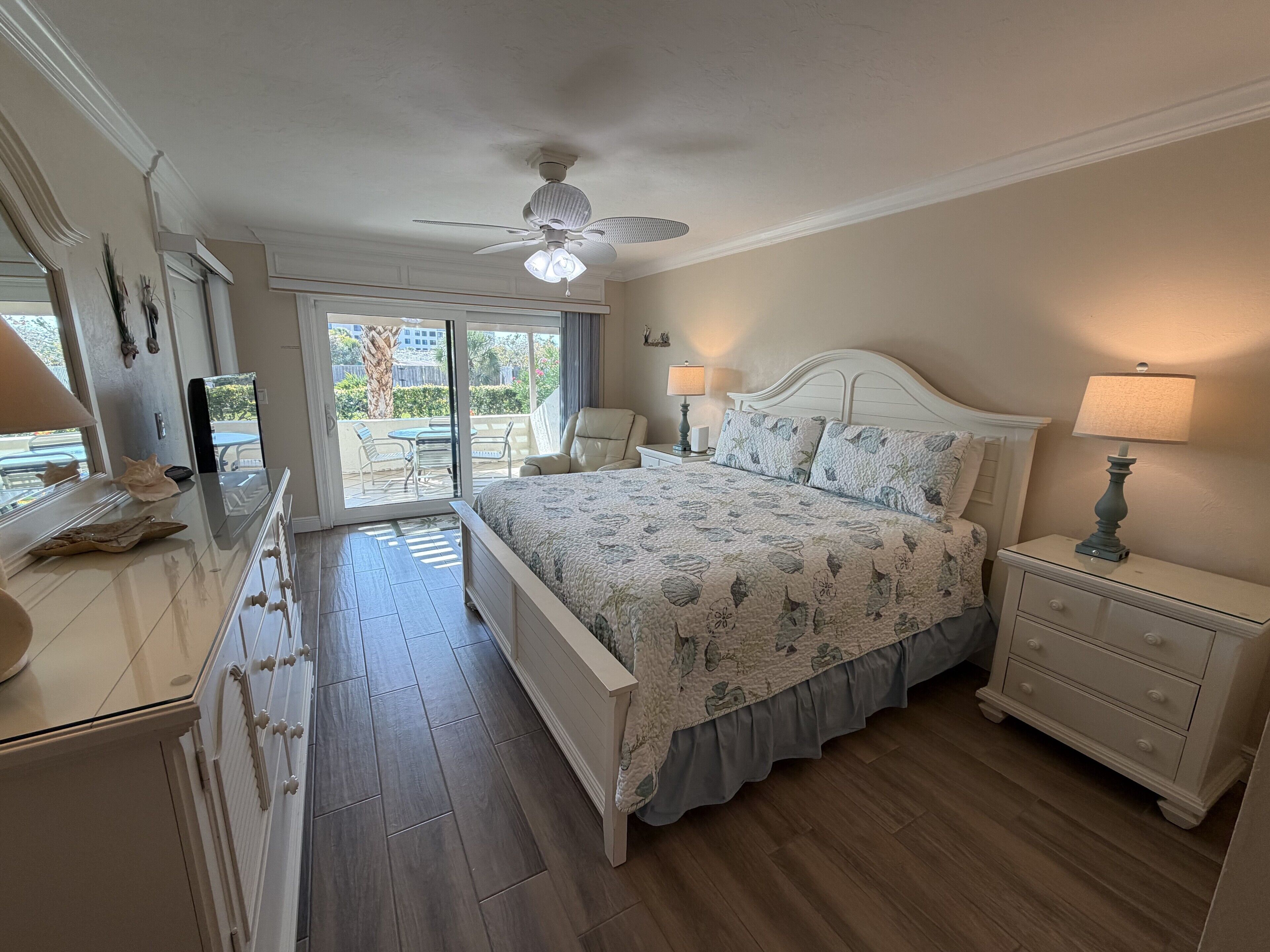 A bedroom with a bed, nightstands, a dresser, and a ceiling fan.