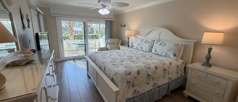 A bedroom with a bed, nightstands, a dresser, and a ceiling fan.