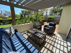 A covered patio with a sofa, a wicker chair, and a small table. - Spacious Contemporary Garden View, Ground Floor Unit (Sarasota)