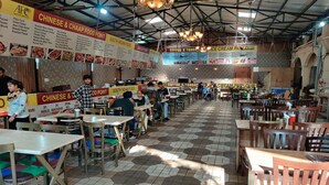 A restaurant with hexagonal patterned flooring, multiple dining areas, and various food and drink options. - Hotel Raj Darbar (Amritsar)