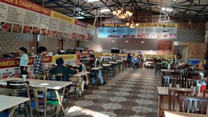 A spacious restaurant with hexagonal tiled flooring, multiple dining areas, and various food and beverage sections. - Hotel Raj Darbar (Amritsar)