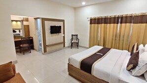 A hotel room with a bed, a desk, a chair, a television, and a bathroom visible through an open door. - Hotel Raj Darbar (Amritsar)