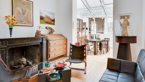 Un salon moderne avec une cheminée, des meubles en bois et des œuvres d’art accrochées aux murs.