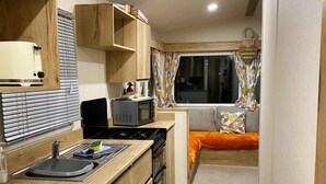 Una cocina pequeña con estufa, microondas y lavamanos.