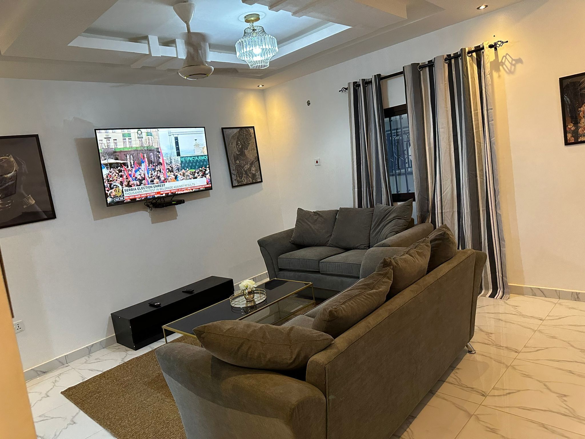 Un salon avec un canapé, une table basse, un téléviseur et un ventilateur de plafond.