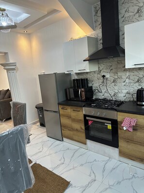 Una cocina moderna con estufa a gas, horno y refrigerador, salpicadero de mármol y armarios de madera.