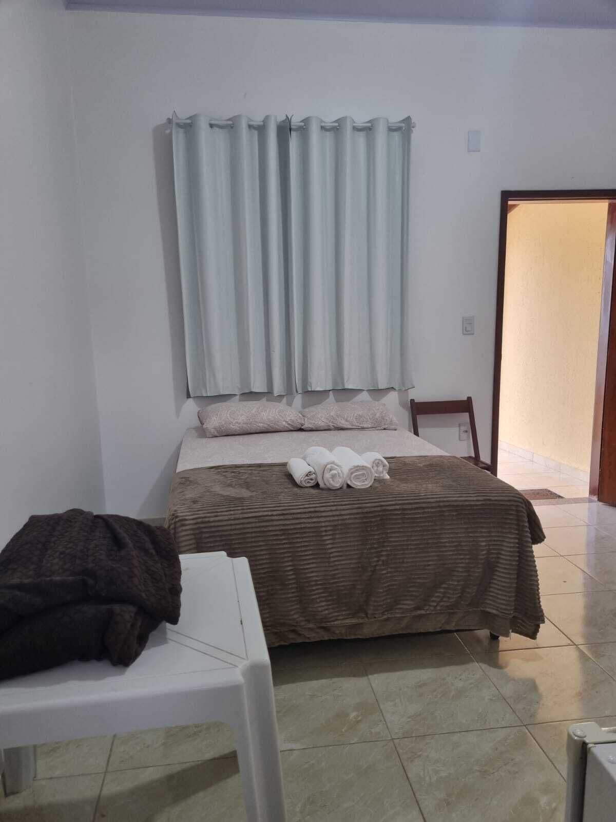 A bedroom with a bed, a chair, a table, and a door.