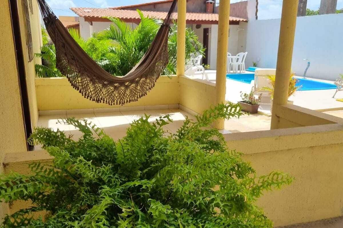 A covered outdoor area with a hammock, potted plants, and a pool.