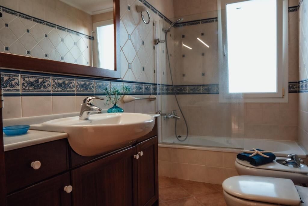 A bathroom with a sink, mirror, shower, and toilet.