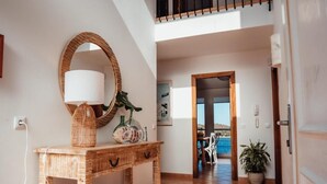 Un couloir avec une console en bois, un miroir rond et une plante en pot.