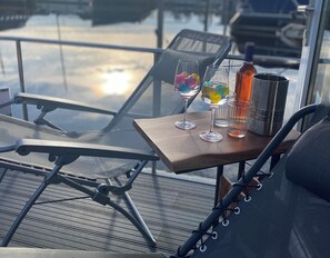 A table with two glasses, a bottle, and a thermos on a deck with chairs. - TOP Ausgestattetes Hausboot mit Dachterrasse in Stavoren am Ijsselmer (Stavoren)