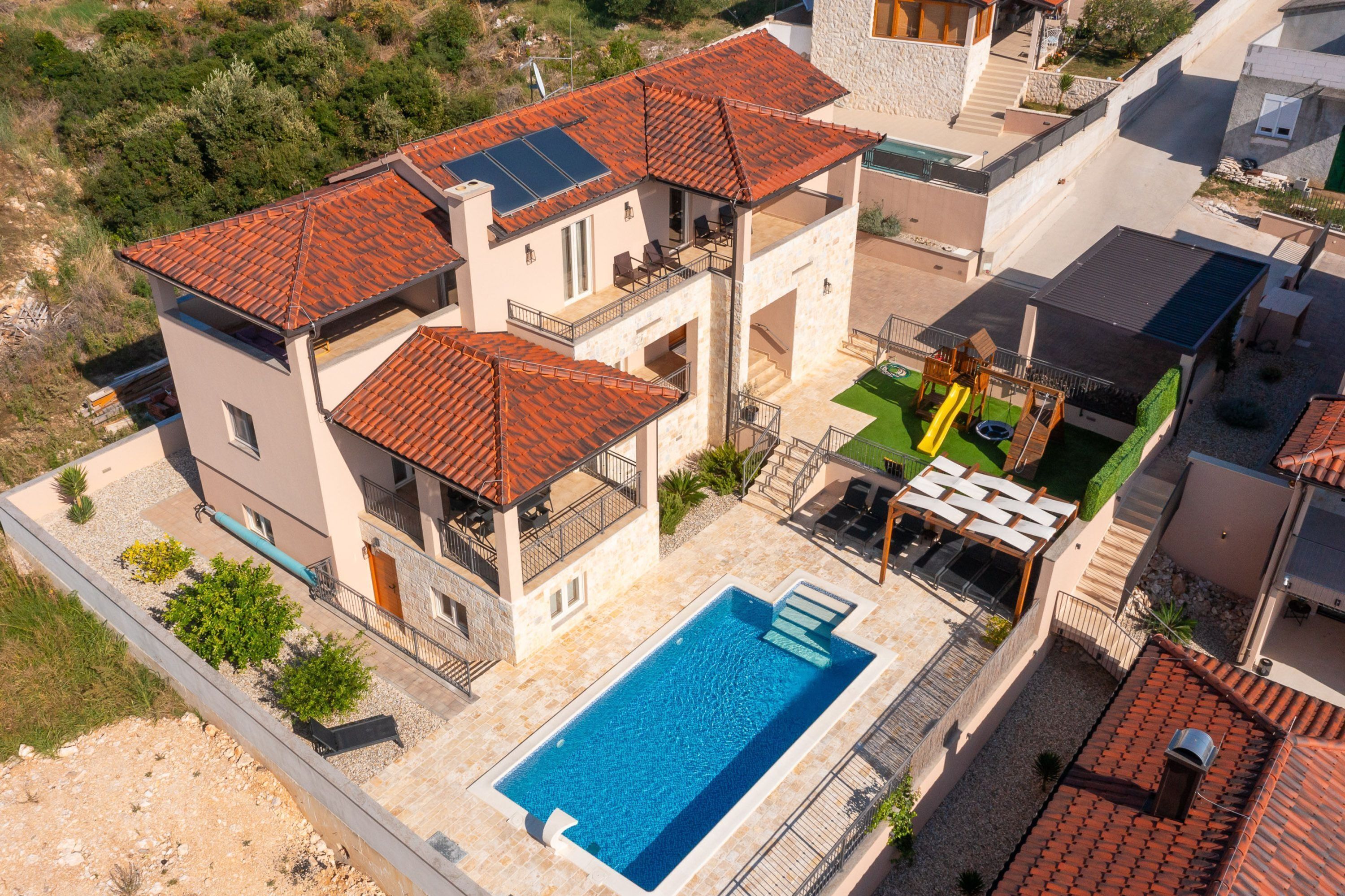 Una casa de varios pisos con piscina, mobiliario exterior y zona verde.