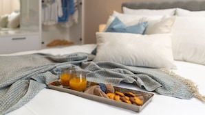 A neatly made bed with pillows and a blanket, a tray with cookies and orange juice, and a wardrobe with hanging clothes. - Villa San Zadarvillas (Sveti Filip i Jakov)