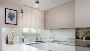 A modern kitchen with white cabinetry, a stainless steel refrigerator, a coffee maker, and a clear glass pendant light. - Villa San Zadarvillas (Sveti Filip i Jakov)