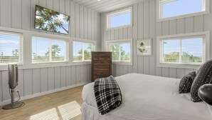A bedroom with a large bed, multiple windows, and a ceiling fan.