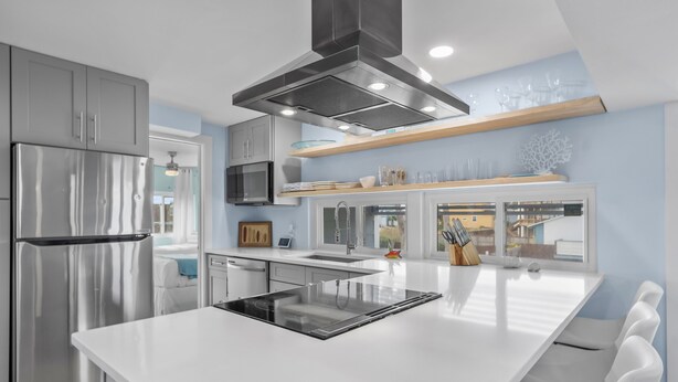 A modern kitchen with a stainless steel refrigerator, a built-in oven, and a large island with a sink.