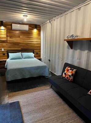 Cozy retreat with a large bed, sofa, and compact shelving.