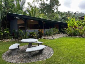 Relax in a serene outdoor setting surrounded by lush tropical plants and a beautifully maintained lawn.