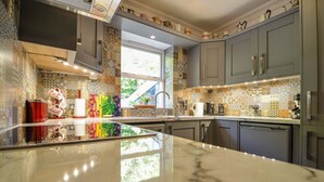 A modern kitchen with a marble countertop, grey cabinets, and colorful backsplash tiles. - The Quay House, Clifden’s oldest building (Clifden)