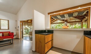 Een moderne keuken met houten kastjes, een zwart aanrecht en een raam met uitzicht op groen.
