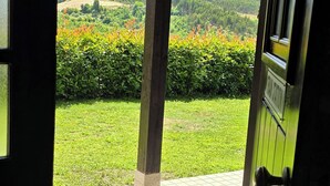 A doorway leading to a covered outdoor area with a view of a green landscape and a hilly background. - Rustic Retreat country house (Tondela)